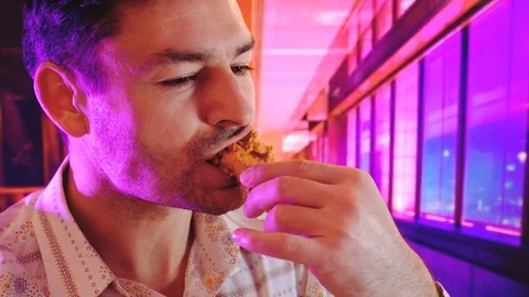 Eats fried chicken in a fast food background with Cool Neon Lights like purple Stock-Footage 101920734