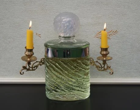 Eau de Rochas big perfume bottle in front of a candelabra with shining candles Stock Photos