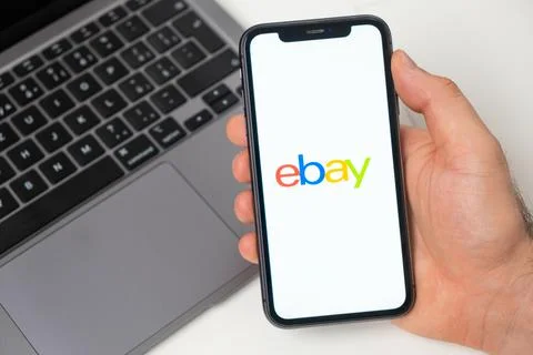Ebay the application is open in the smartphone. The man is holding a mobile Stock Photos