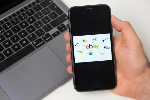 Ebay the application is open in the smartphone. The man is holding a mobile Stock Photos