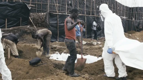 EBOLA: Burial team buries corpse while wearing protective equipment (PPE) Video stock 90294696