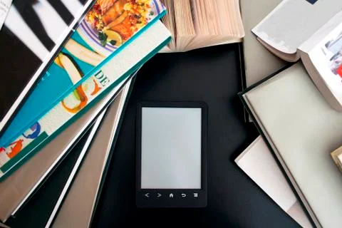 Ebook with a gray screen on the black table among the many paper books Stock Photos