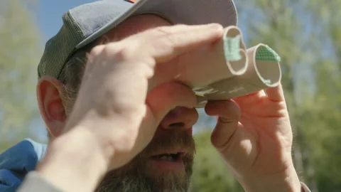 Eccentric caucasian man with beard looking through handmade cardboard binoculars Stock Footage 311456614
