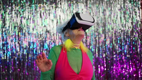 Eccentric grandma in VR headset exploring immersive virtual reality experience Stock Footage 331216555