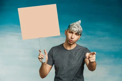 An eccentric man in a foil hat scaredly grabs in hands with his hands. wide o Stock Photos