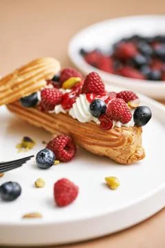 Eclair cake. Sweet delicious eclairs, traditional French pastries with cream and Stock Photos
