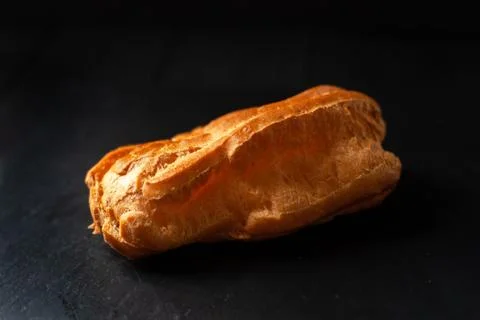 Eclair with cream on a black background. Stock Photos