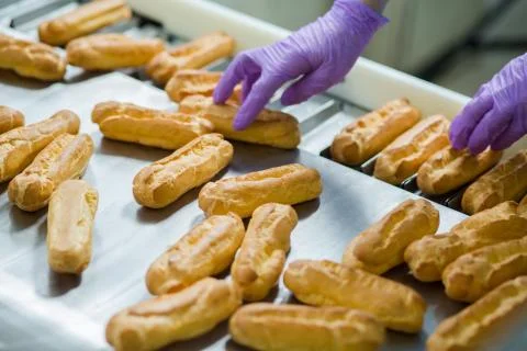 Eclair shells beside conveyor belt. Stock Photos