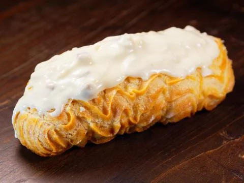 Eclair with white chocolate icing. One eclair on a wooden vintage background. Foto stock