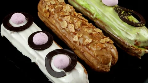 Eclairs with glaze, chocolate, nuts and pistachios no top, closeup, loop Stock Footage 63853269