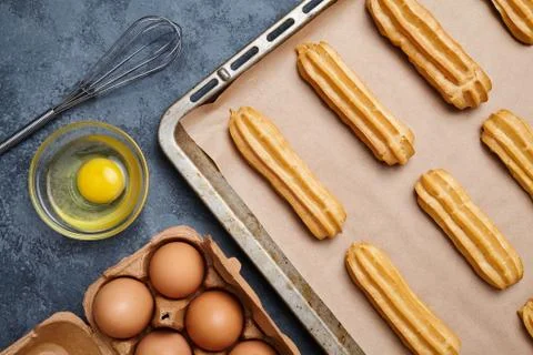 Eclairs or profiterole preparing with eggs on baking sheet background Stock Photos