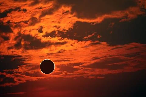 Eclipse on the dark red sunset sky and transparent cloud Stock Photos