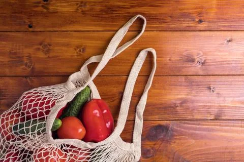 Eco bag string bag with vegetables cucumbers and tomatoes on a wooden background Stock Photos