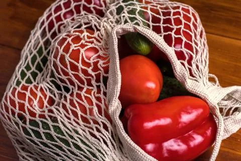 Eco bag string bag with vegetables cucumbers and tomatoes on a wooden background Stock Photos