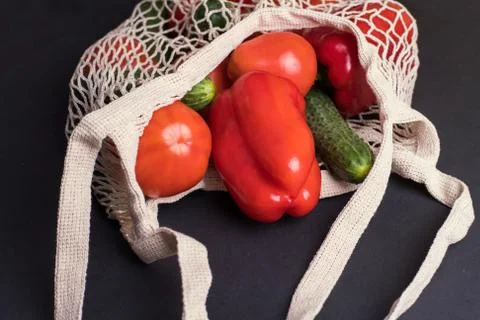 Eco bag string bag with vegetables cucumbers and tomatoes on a black background Stock Photos