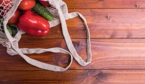 Eco bag string bag with vegetables cucumbers and tomatoes on a wooden backgro Stock Photos