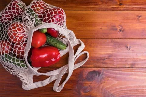 Eco bag string bag with vegetables cucumbers and tomatoes on a wooden background Stock Photos
