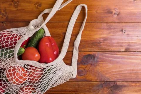 Eco bag string bag with vegetables cucumbers and tomatoes on a wooden background Stock Photos