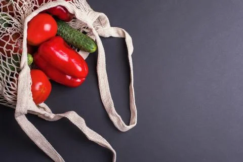 Eco bag string bag with vegetables cucumbers and tomatoes on a black background Stock Photos