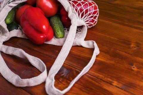 Eco bag string bag with vegetables cucumbers and tomatoes on a wooden background Stock Photos