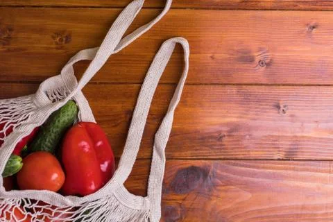 Eco bag string bag with vegetables cucumbers and tomatoes on a wooden backgro Stock Photos