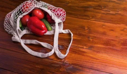 Eco bag string bag with vegetables cucumbers and tomatoes on a wooden backgro Stock Photos