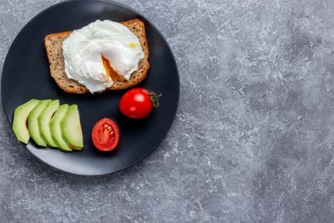 Eco breakfast with a poached egg on bread with seeds on a black plate Stock Photos