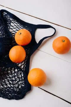 Eco- friendly bag string bag with oranges on a wooden background Foto stock