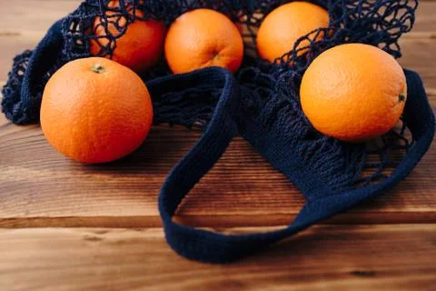 Eco- friendly bag string bag with oranges on a wooden background Foto stock