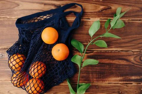 Eco- friendly bag string bag with oranges on a wooden background Stock Photos