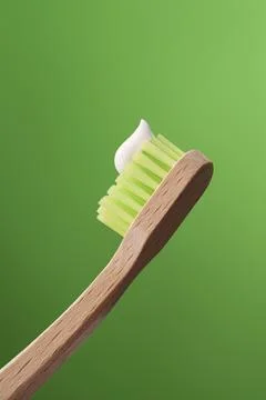 Eco-friendly Bamboo Toothbrush with Toothpaste on a Green Background. Stock Photos