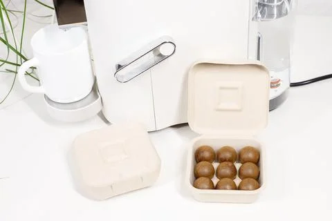 Eco-friendly coffee capsules in compostable packaging near a coffee machine Stock-Fotos