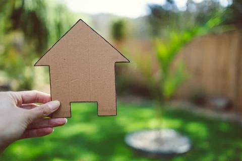 Eco-friendly construction, hand holding house icon under the sun with garde.. Stock Photos