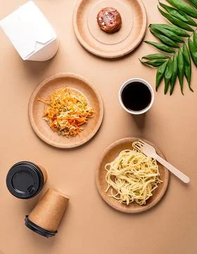 Eco friendly disposable tableware full of food on brown background Stock Photos