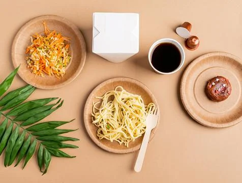 Eco friendly disposable tableware full of food on brown background Stock Photos