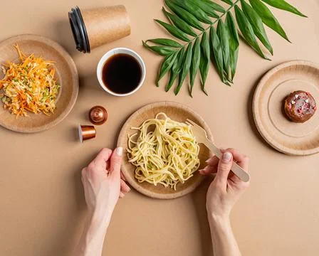 Eco friendly disposable tableware full of food on brown background Stock Photos