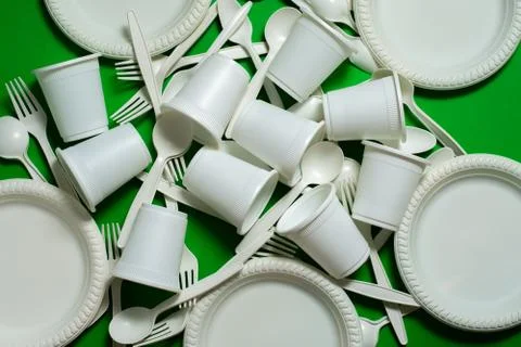 Eco-friendly disposable tableware on a green background. Stock Photos