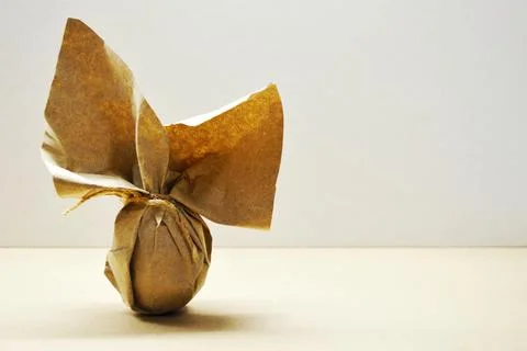 Eco-friendly Easter gift. Egg wrapped in kraft paper stands on light backgrou Fotos de archivo