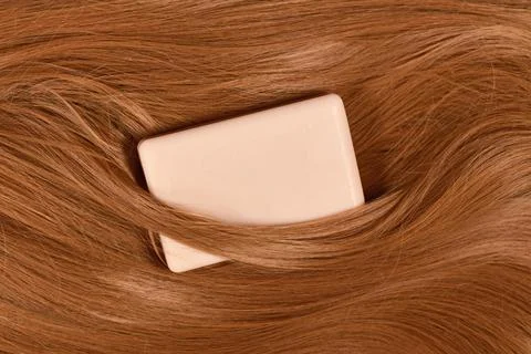 Eco friendly solid shampoo bar surrounded by healthy brunette hair Foto stock