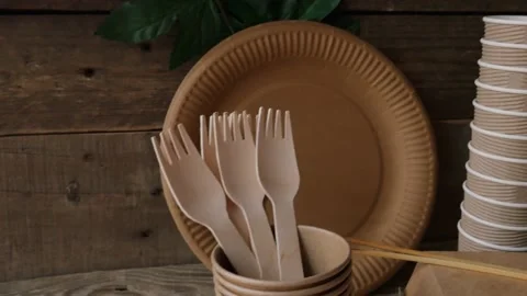 Eco tableware. The forks lie on a craft plate on a wooden background with a leaf Video stock 155554379