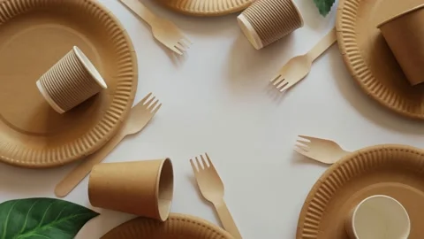 Eco tableware. Forks lie in a glass, stand craft plates on a wooden background w Stock Footage 155810198
