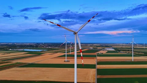 Eco wind generators on dark patchwork fields at dusk. Aerial panorama of 動画素材 339018580