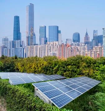 Ecological energy renewable solar panel plant with urban landscape landmarks Stock Photos