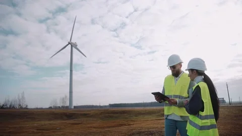 Ecological engineers use digital tablet and talk at the windmill field Stock Footage 171968934