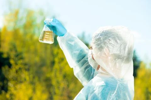 Ecologist determines the properties of water visually, the sample is taken in Stock Photos