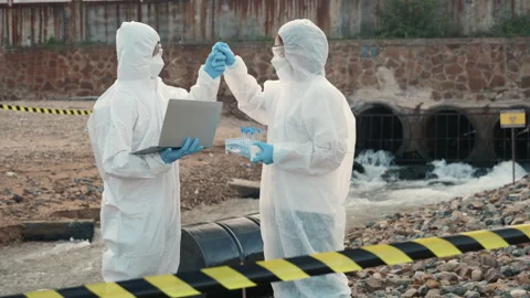 Ecologist sampling water from the river with test tube and save data to laptop Stock Footage 249779798