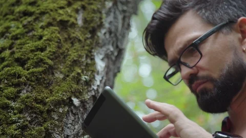 Ecologist studies moss on a tree and writes data to a tablet computer. Stock Footage 95286447