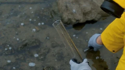 Ecologist takes in a test tube of water from the city river examines contents Stock Footage