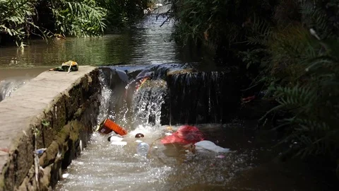 Ecology catastrophe swimming garbage in small asian river in the city slowmotion Stock Footage 101242985