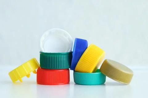 Ecology. Plastic multi-colored caps for bottles on a gray background. Close-u Stock Photos